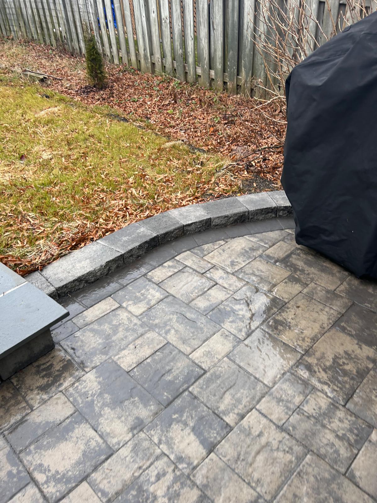 Paver patio edge beside a fallen-leaf bed in autumn by Kaeler